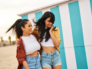 portrait of two beautiful cheerful young women resting on the beach. laughing girlfriends in the sea