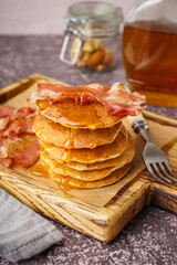 Wall Mural - Wooden board of tasty pancakes with bacon and maple syrup on table
