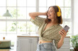 © Pixel-Shot - Cool young woman with mobile phone listening to music and dancing in kitchen
