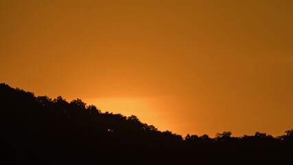 Wall Mural - Breathtaking beauty of the sun rising time lapse video over a rugged mountain ridge on a cloudy morning.