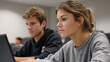 © Kliapko_Photo - Two students in a classroom at university, one using a laptop, captured from a low angle.