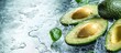 © tetxu - Fresh avocado cut in half with water drops splashing on a green background