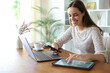© Antonioguillem - Happy woman using multiple devices on a table at home