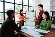 © Dino - Brainstorming of young modern group. Team meeting to achieve goal. Business people discussing finance business and analysis. Teamwork concept in modern office. Calculating personal tax for client.