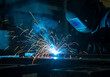 © xaras - A welder in protective gear using a welding torch, creating sparks and light.