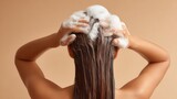 Woman applying shampoo, in hair with rich foam, enjoying refreshing shower massaging serene bathroom, back view