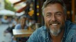 © Artistic Visionary - Smiling man, blue eyes, beard, denim shirt, blurred cafe background