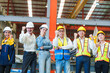 © AU USAnakul - Group of diverse industrial workers and engineers in safety gear celebrating success inside factory, symbolizing teamwork, unity, and achievement in manufacturing.