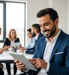 © picturehome - Happy positive confident Middle Eastern businessman working with tablet in office meeting room with colleagues talking behind, browsing Internet, enjoying online technology, smiling