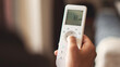 © busra - Hand with remote control directed on air conditioner. Home air conditioning concept