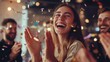 © Ta stodio - A joyful young woman claps and laughs amid colorful confetti while celebrating with friends in a lively, festive indoor setting.