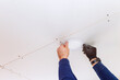 © ungvar - Skilled electrician is installing circular ceiling light fixture in modern home interior.