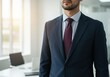 © Smartra - Confident businessman in a dark suit and burgundy tie standing in an office