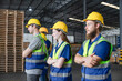© AU USAnakul - Group of multiethnic warehouse workers standing in confident pose with arms crossed, wearing safety vests and helmets in organized storage facility