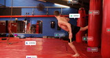 Shirtless teen performing side kick to punching bag in martial arts gym, copy space