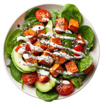 Healthy salad with roasted sweet potato, avocado, spinach, and cherry tomatoes. A light dressing of creamy sauce with seeds is drizzled over the dish