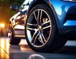 © desain - Close-up of a modern car's alloy wheel.  Sleek, metallic blue SUV,  low angle,  glowing light reflections