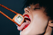 © VICHIZH - Sensual woman enjoying sushi with chopsticks, vibrant colors, close-up, playful mood, focus on food and emotion. Sushi experience, culinary delight.