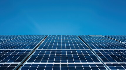 A low angle view of a solar panel array against a clear bright blue sky on a sunny day outdoors