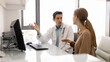 © fizkes - Serious male Latin physician explaining insurance terms to young female patient, pointing at computer monitor at clinic office workplace, telling about diagnosis, effective treatment. Banner shot
