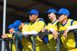 © Wavebreak Media - Male baseball teammates leaning on fence at baseball dugout in yellow jerseys holding gloves