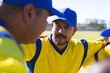 © Wavebreak Media - Male baseball teammates huddling on baseball diamond in yellow jerseys and blue caps