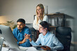 © puhhha - Group Of Professionals Discussing A Project Around A Computer In Modern Office, Exhibiting Collaboration, Teamwork, And Problem-Solving Concepts, With Focused Expressions Representing Innovation