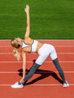 © Yevhen - Young woman stretching before her run. Sportswoman stretching before run on stadium. Woman in sports outfits doing stretching before workout outdoor in the city stadium a healthy lifestyle