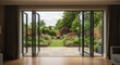 © Jawad - Beautiful garden and patio in summer seen from stylish designer room through bifold doors.