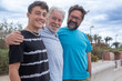 © luciano - Portrait of a carefree family group of three multigenerational people, father, son and nephew smiling together outdoors by the seaside feeling joy, freedom and vacation