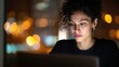 © tao - A close-up portrait of an Asian woman with curly hair and dressed in black, working on her laptop in the office at night, with soft lighting shining on her face, creating a cinematic atmosphere.