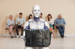 © New Africa - Robot with bag against group of people waiting for job interview, selective focus. Artificial intelligence in recruitment