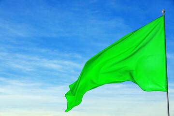Wall Mural - green flag waving against blue sky outdoors
