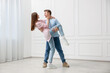 © New Africa - Happy couple dancing together near white wall at home