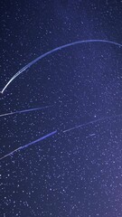 Wall Mural - a mesmerizing video of a starry night sky with streaking meteors, captured from a low-angle perspect