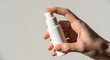 © Alif - A hand pressing a white pump bottle dispenser for cosmetic cream or lotion on a clean background.