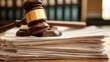 © Angelo - A wooden gavel resting on a stack of legal documents in a courtroom setting.