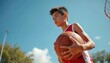© Viktor - Young basketball player holds ball, looks forward with determination on sunny outdoor court. Athletic youth ready for game action, showing passion for sport and fitness.