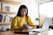 © fizkes - Smiling Indian woman using smartphone seated at workplace in office, lead positive interaction, enjoy personal communication, check email or messages, responding to professional correspondence via app