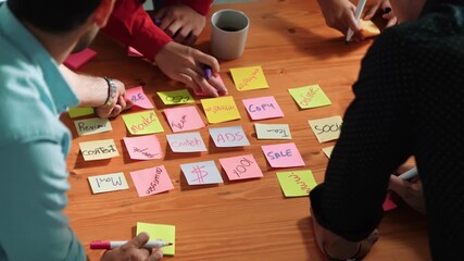 Wall Mural - top down aerial view of creative people hands writing idea on sticky notes at meeting table. close u