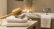© Ahmad - Relaxing spa scene with towels, brush and pumice stone in a muted bathroom setting.