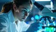 © photostockatinat - A scientist is deeply focused on her work under the microscope. She is intently observing a sample with a serious expression. This image highlights scientific innovation