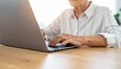 © photostockatinat - An elderly person working on a laptop, showcasing the use of technology across generations. The hands are positioned on the keyboard