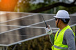 © Sittisak - Energy Technician with Radio at Installation Site.the supervision and operational aspects of solar energy systems, under natural daylight.