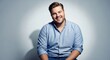 © Таня Андреева - Cheerful plus-size man in light blue button-down shirt laughing against gray studio background. Body positivity, confidence, diversity concept.
