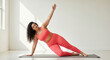© Николай Срибяник - Beautiful plus-size woman in coral activewear performing side plank yoga pose on mat in bright white studio. Body positivity, inclusive fitness, wellness concept.
