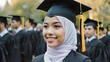 © Misnara - Young Muslim Woman in Graduation Cap and Hijab Smiling During Outdoor Commencement Ceremony with Other Students in Background