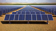 © SUDARNO - Vast solar panel farm stretches across a desert landscape, rows of panels aligned in a straight line.  Sunny day,  with a horizon of dunes and a grassy plain beyond