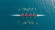 © Nuraya - Team of four rowers in sync powering a racing shell through calm blue water, an aerial view of synchronized athletic effort.