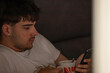 © carballo - young man with mobile phone or smartphone at home on the sofa